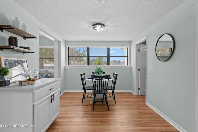 dining area with a wealth of natural light, baseboards, a textured ceiling, and light wood-style flooring