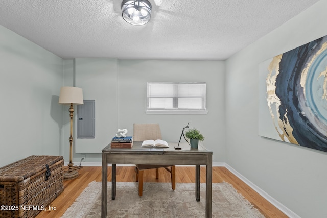 office area featuring electric panel, light wood-type flooring, baseboards, and a textured ceiling