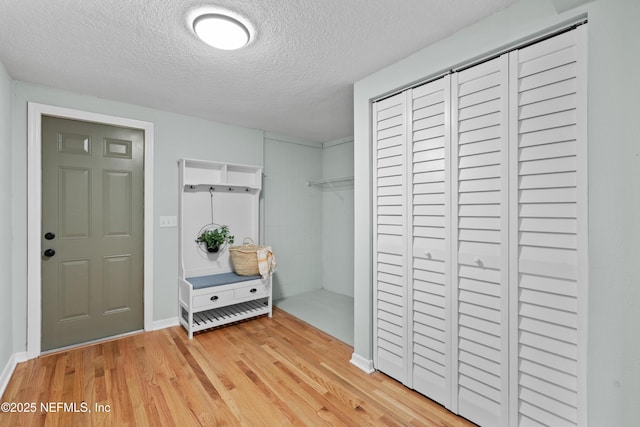 interior space featuring light wood-type flooring, baseboards, and a textured ceiling