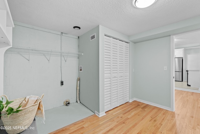 laundry area featuring visible vents, washer hookup, a textured ceiling, light wood-style floors, and laundry area