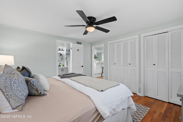 bedroom with visible vents, two closets, wood finished floors, and a ceiling fan