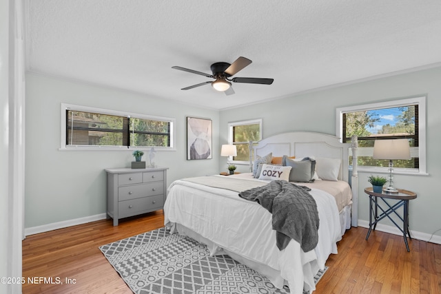 bedroom featuring baseboards, multiple windows, and wood finished floors