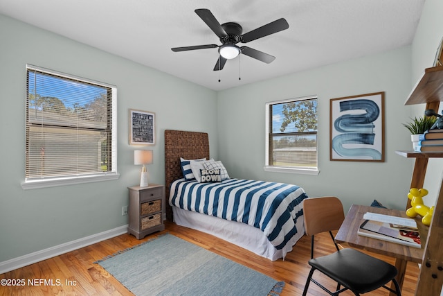 bedroom with light wood-type flooring, baseboards, and a ceiling fan