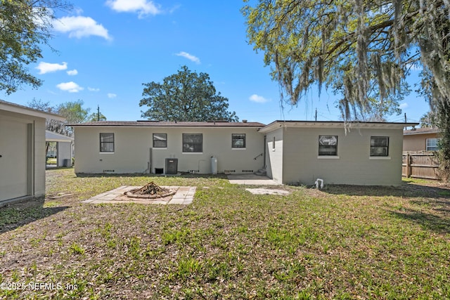 back of property with central air condition unit, a lawn, fence, an outdoor fire pit, and crawl space