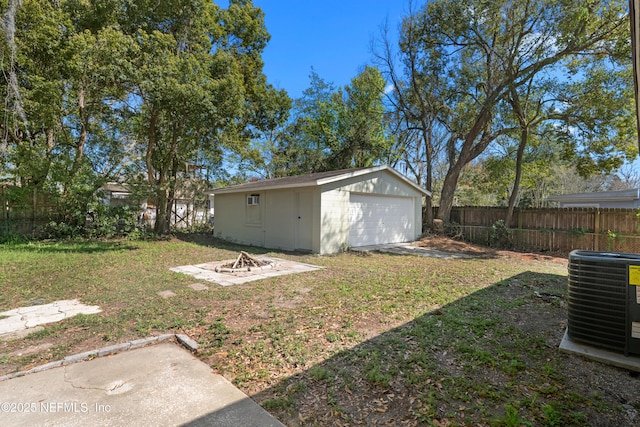 view of yard with an outbuilding, central AC unit, fence, and a detached garage