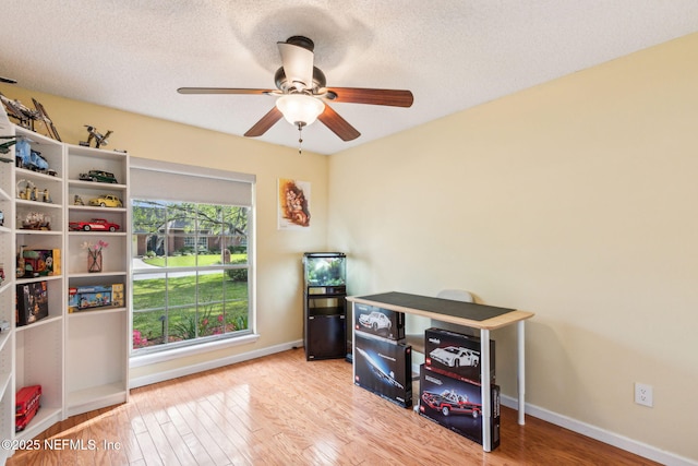 misc room with ceiling fan, baseboards, a textured ceiling, and wood finished floors