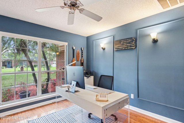 home office featuring a textured ceiling, wood finished floors, visible vents, and ceiling fan