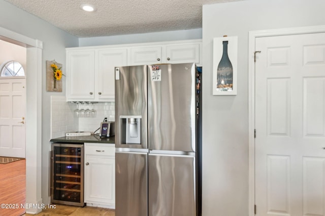 kitchen with dark countertops, white cabinets, beverage cooler, and stainless steel refrigerator with ice dispenser