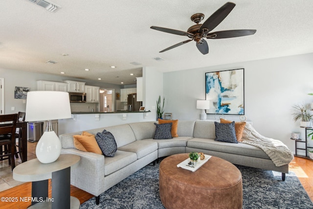 living area featuring visible vents, recessed lighting, light wood-style floors, and a ceiling fan