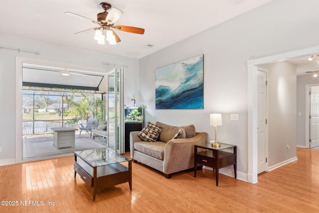 living room featuring light wood-type flooring, baseboards, and a ceiling fan