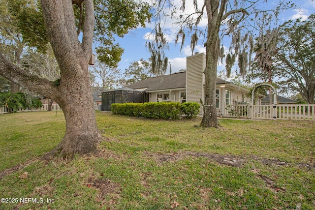 view of yard featuring a gate, glass enclosure, and fence