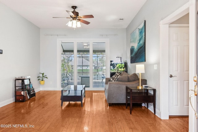 living room with baseboards, light wood-type flooring, and ceiling fan