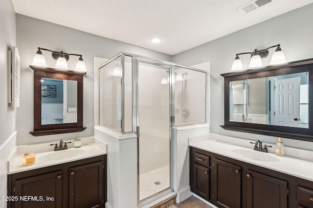 bathroom featuring visible vents, a shower stall, a textured ceiling, and a sink