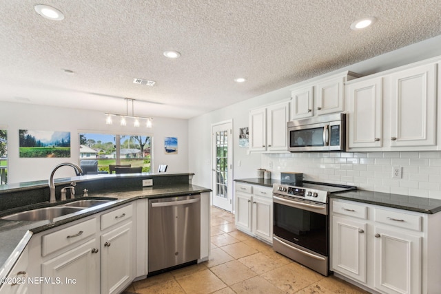 kitchen featuring dark countertops, visible vents, appliances with stainless steel finishes, and a sink