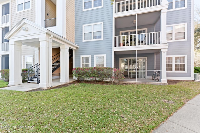 exterior space featuring a balcony, stairway, and a lawn