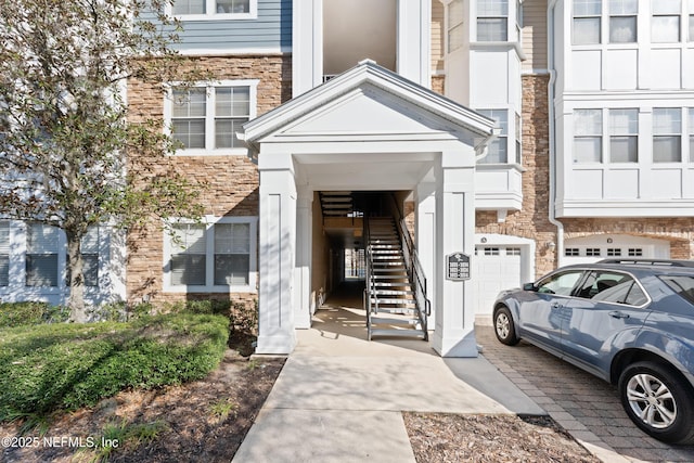 entrance to property featuring a garage and stone siding