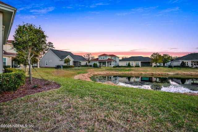 yard at dusk featuring a water view