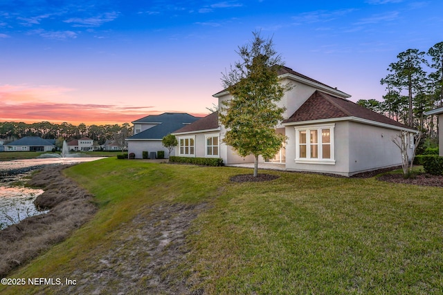 back of house featuring a lawn and stucco siding