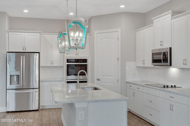 kitchen featuring decorative backsplash, light wood-style flooring, appliances with stainless steel finishes, white cabinets, and a sink