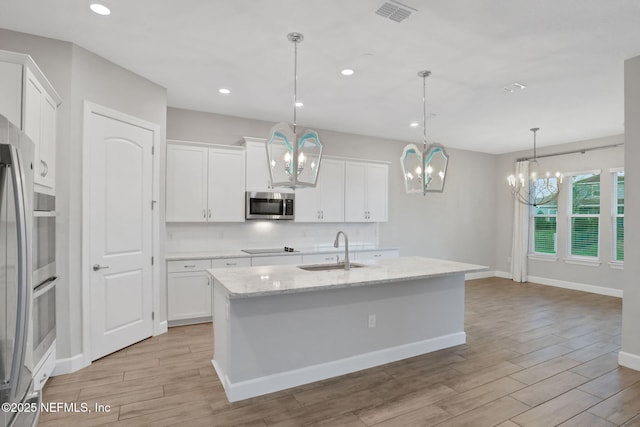 kitchen with visible vents, wood tiled floor, a sink, decorative backsplash, and appliances with stainless steel finishes