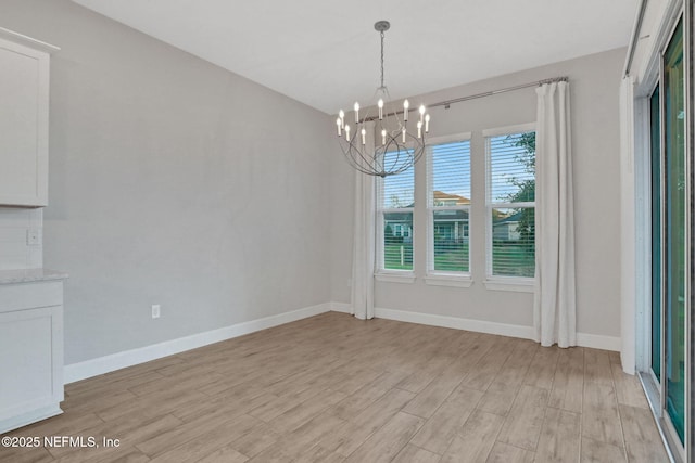 unfurnished dining area with light wood-type flooring, baseboards, and a chandelier