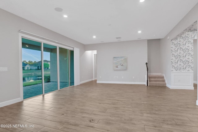 empty room featuring recessed lighting, stairway, baseboards, and light wood finished floors