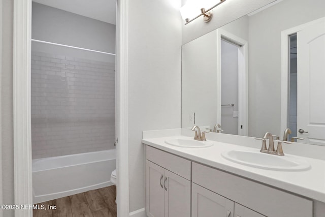 bathroom with double vanity, toilet, wood finished floors, and a sink