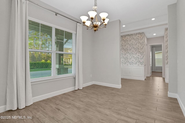 unfurnished room featuring light wood-style flooring, recessed lighting, a wainscoted wall, and a chandelier