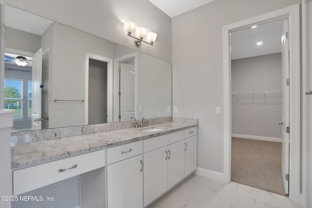 bathroom with marble finish floor, vanity, baseboards, ceiling fan, and a spacious closet