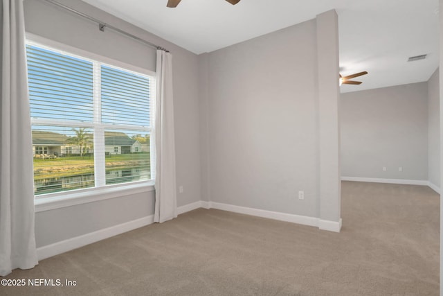 unfurnished room featuring light carpet, visible vents, baseboards, and a ceiling fan