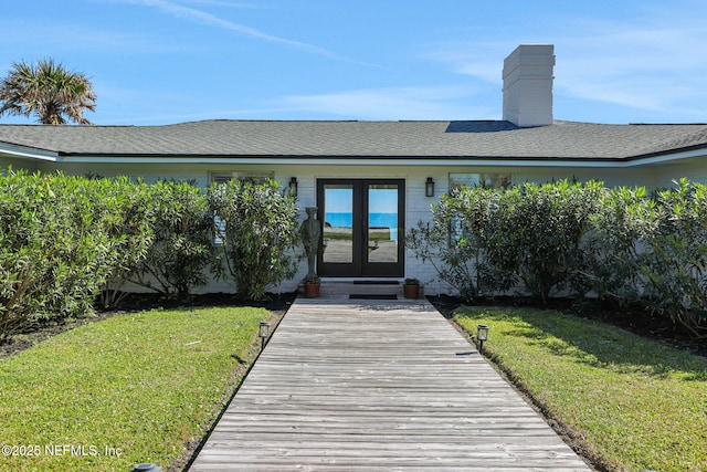 back of property featuring french doors, a yard, and a chimney