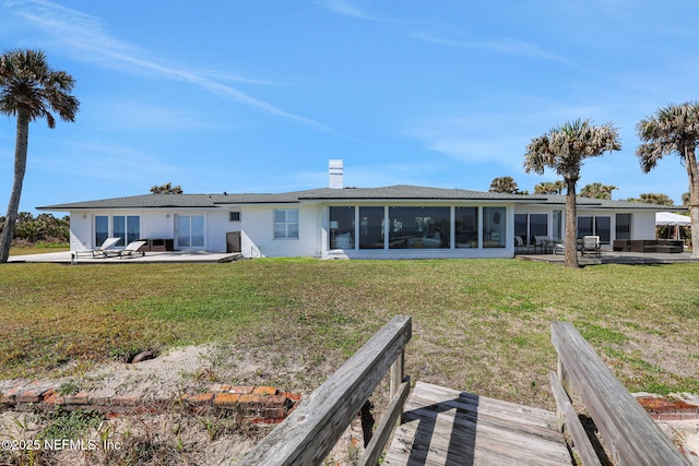 rear view of house with a yard, a chimney, a patio, and a sunroom