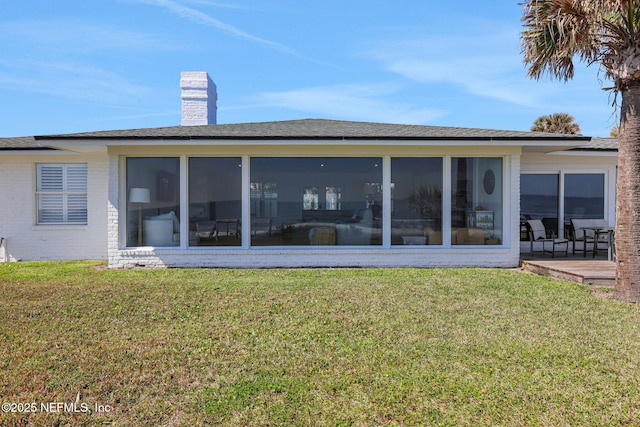 back of house with a chimney, a yard, and a sunroom