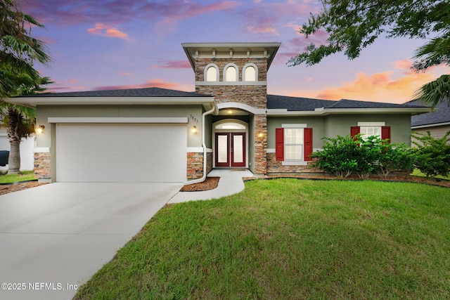 view of front of home featuring driveway, an attached garage, stucco siding, french doors, and a lawn