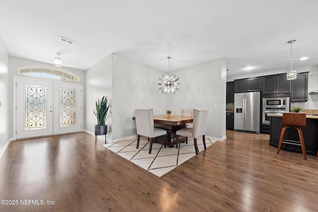 dining space with wood finished floors, visible vents, baseboards, french doors, and a chandelier