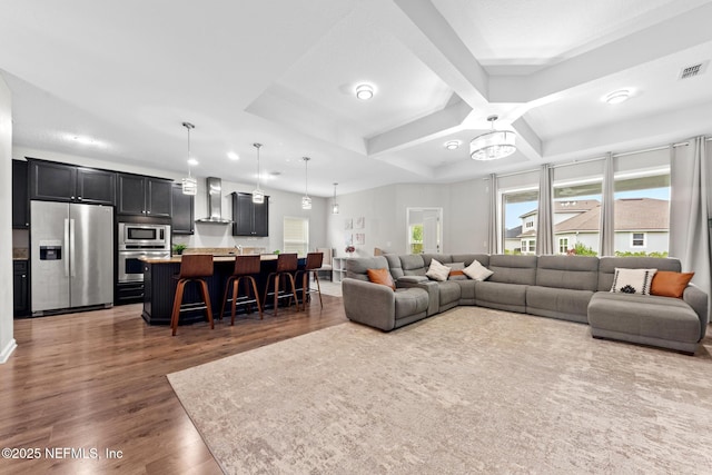 living area with beam ceiling, wood finished floors, visible vents, and coffered ceiling