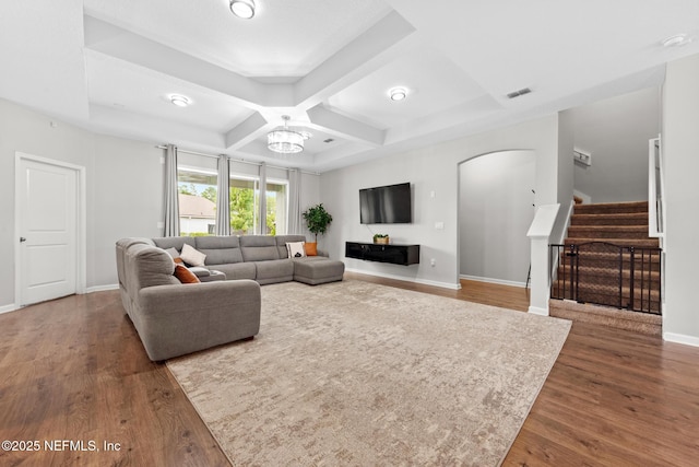 living room featuring visible vents, coffered ceiling, wood finished floors, stairway, and arched walkways