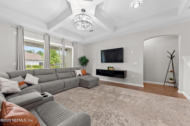 living room with beam ceiling, wood finished floors, arched walkways, and baseboards