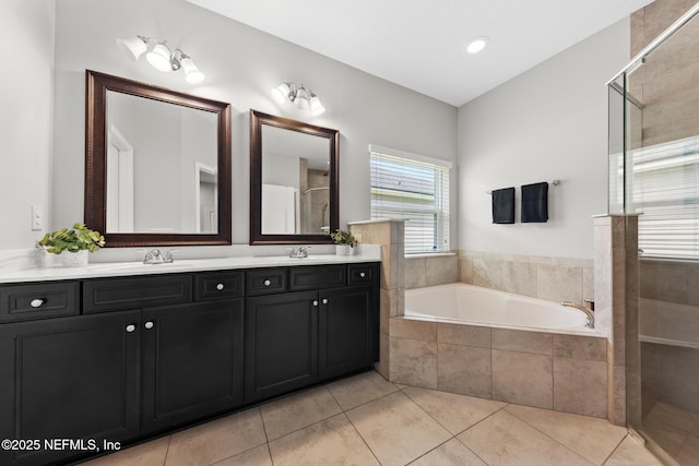 full bath featuring tile patterned flooring, a shower stall, a garden tub, double vanity, and a sink