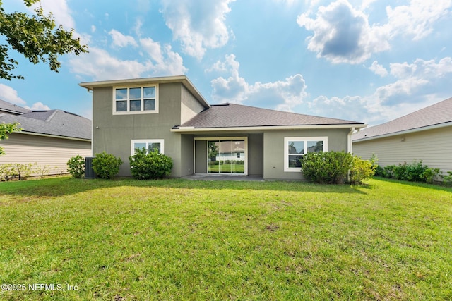 back of property featuring a lawn, roof with shingles, and stucco siding