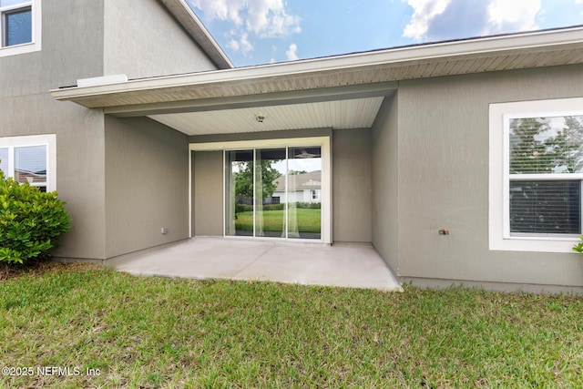 rear view of property with a yard, stucco siding, and a patio