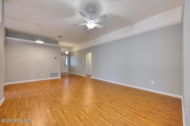 empty room featuring a ceiling fan, light wood-style floors, visible vents, and baseboards