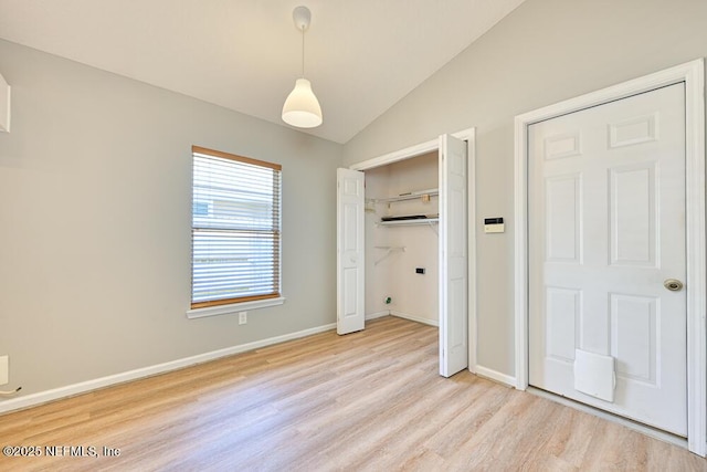 unfurnished bedroom with a closet, wood finished floors, baseboards, and vaulted ceiling