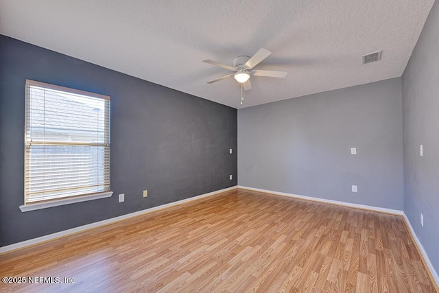 empty room featuring baseboards, visible vents, ceiling fan, a textured ceiling, and light wood-type flooring