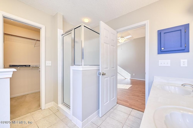 bathroom featuring a sink, a ceiling fan, a shower stall, and tile patterned flooring