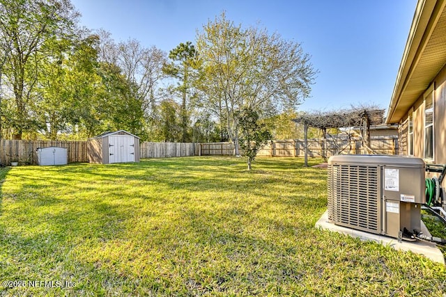 view of yard with a storage shed, an outbuilding, central air condition unit, and a fenced backyard