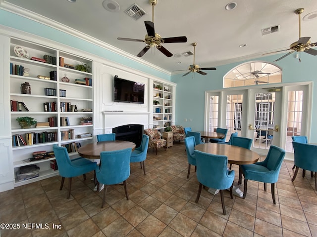 tiled dining room with visible vents, built in shelves, a fireplace, and crown molding