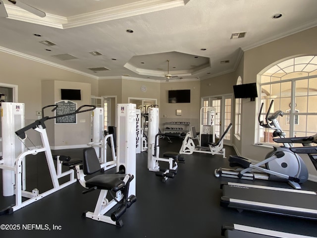 gym featuring baseboards, visible vents, a tray ceiling, ornamental molding, and ceiling fan