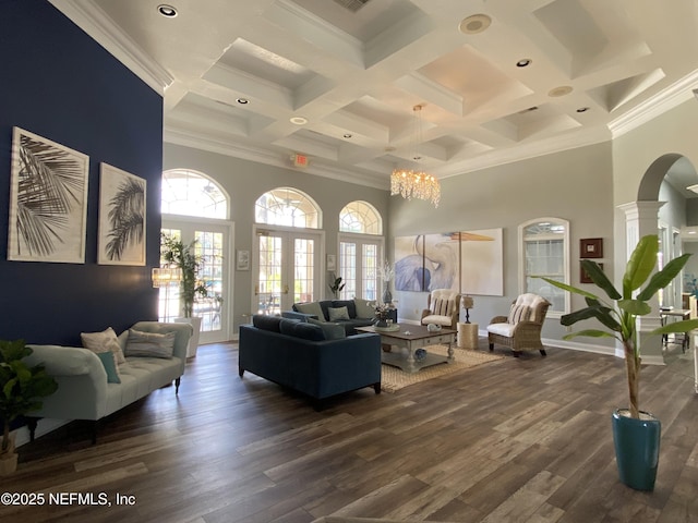 living area with a wealth of natural light, dark wood-type flooring, a high ceiling, and arched walkways