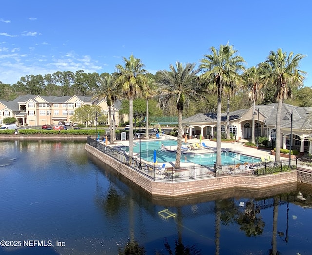 community pool with a patio area, a residential view, and a water view